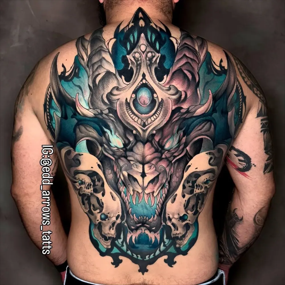 Full-back tattoo of a horned dragon with teal accents between two skulls, neo-traditional color